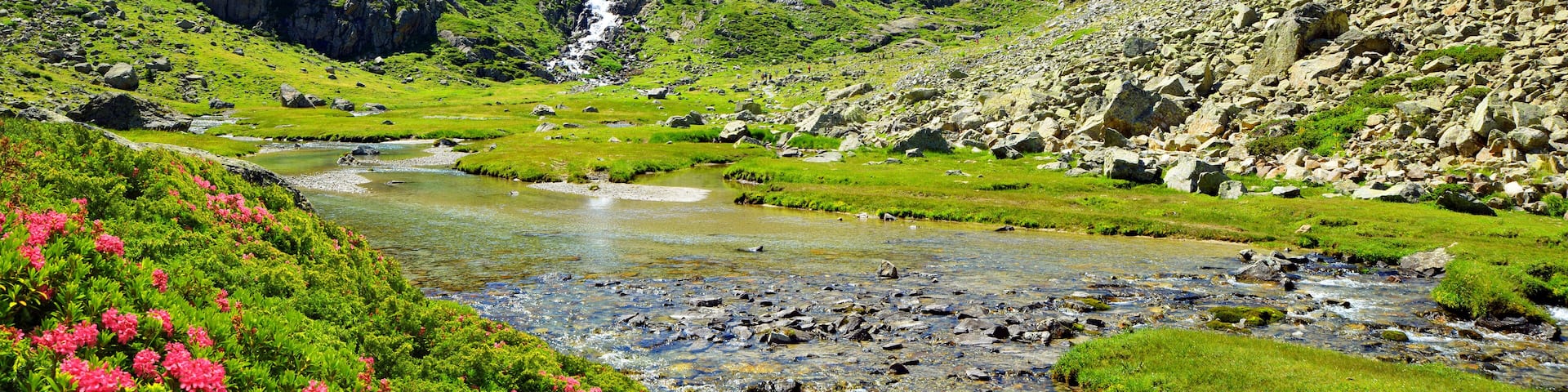 A mountainous landscape with a river, rocky terrain, and a waterfall.