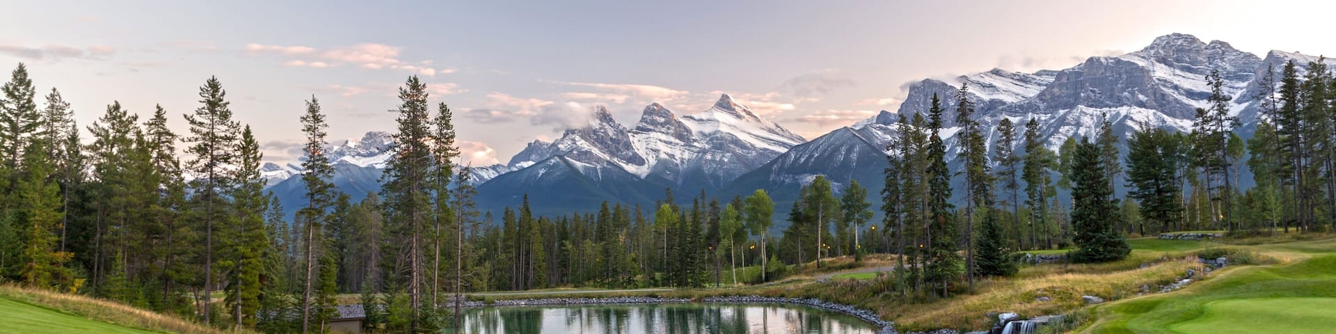Silvertip Golf Course Green and Distant Landscape View of Three Sisters Snowy Mountain Tops above Town of Canmore in Foothills of Rocky Mountains Alberta Canada