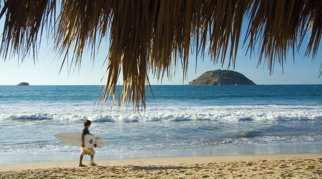 A surfer walking on a beach in Rincon de Guayabitos, Mexico
