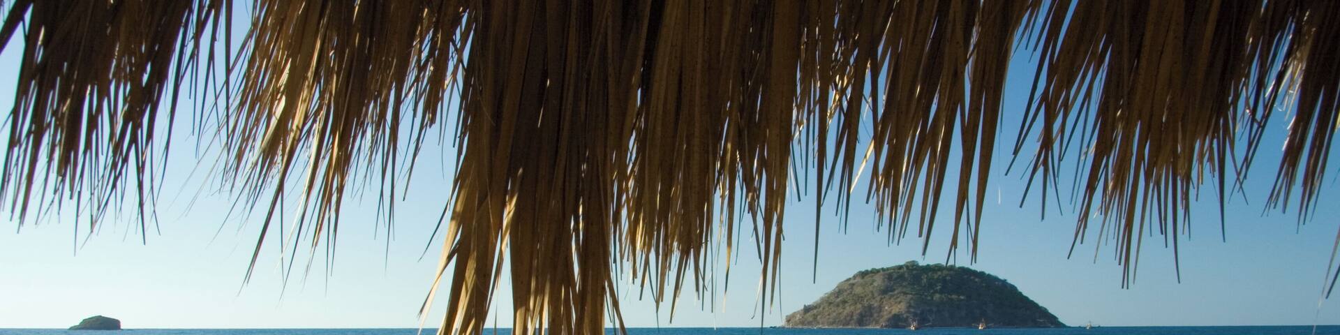 A surfer walking on a beach in Rincon de Guayabitos, Mexico