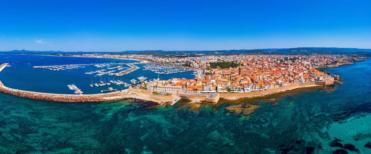 Aerial view over Alghero old town, cityscape Alghero view on a beautiful day with harbor and open sea in view. Alghero, Italy. Panoramic aerial view of Alghero, Sardinia, Italy.