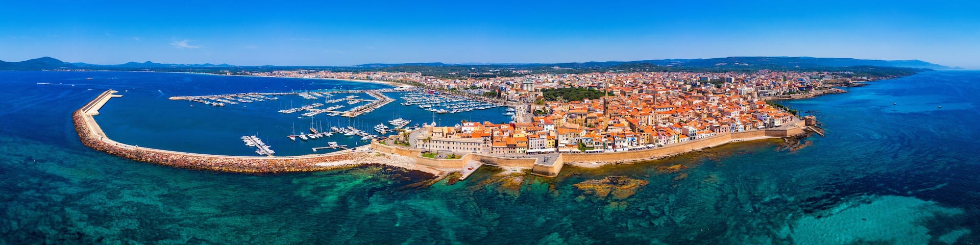 Aerial view over Alghero old town, cityscape Alghero view on a beautiful day with harbor and open sea in view. Alghero, Italy. Panoramic aerial view of Alghero, Sardinia, Italy.
