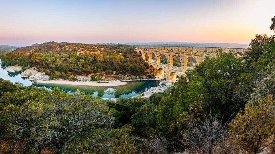 Pont du Gard, ancient Roman aqueduct bridge, elevated panoramic view, river bend and arches, early morning golden light, Gorges du Gardon, natural landscape, UNESCO Biosphere Reserve, Provence, France