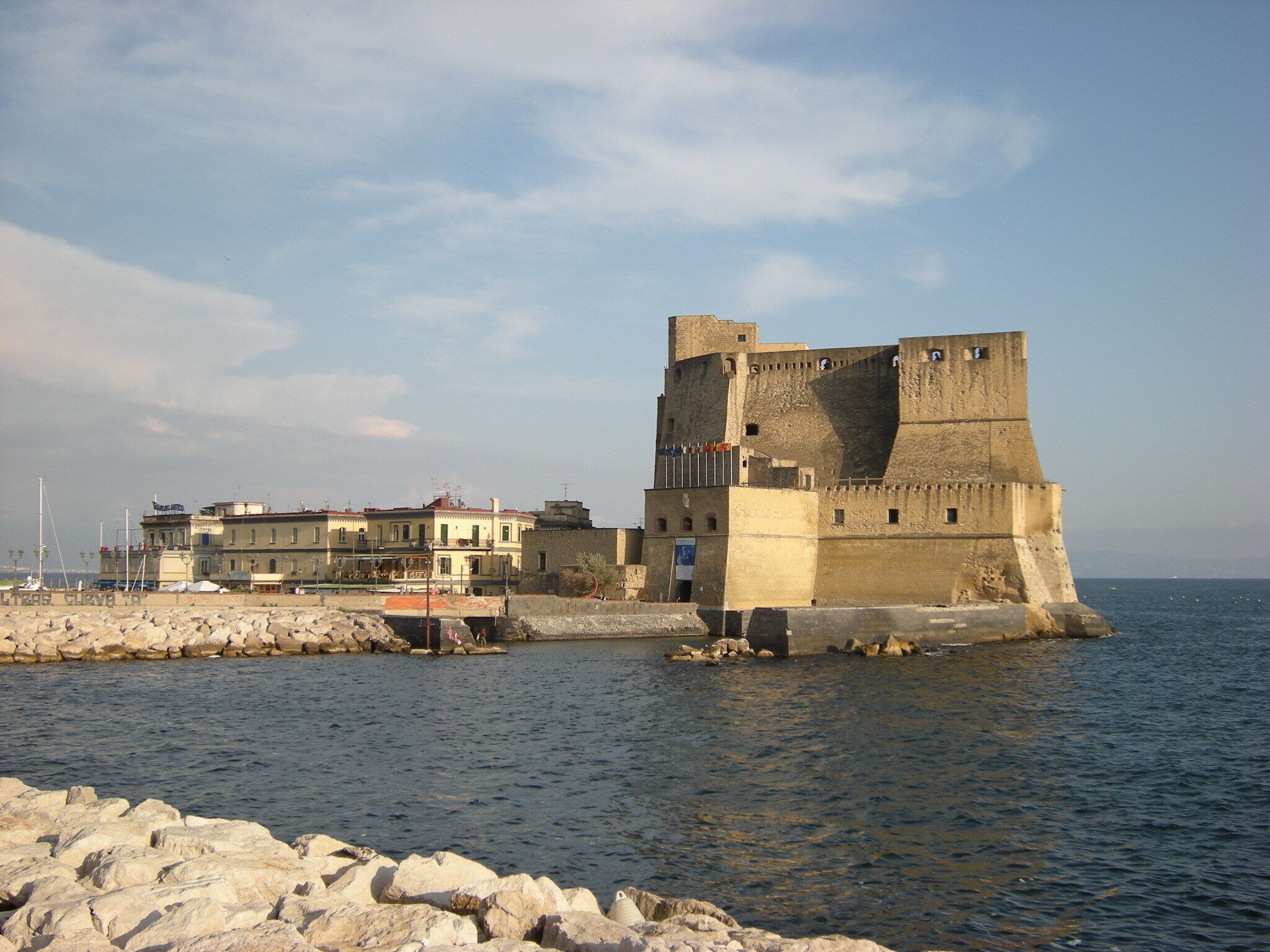 Una fortaleza costera con una torre imponente y un muro amurallado, con vistas al mar.