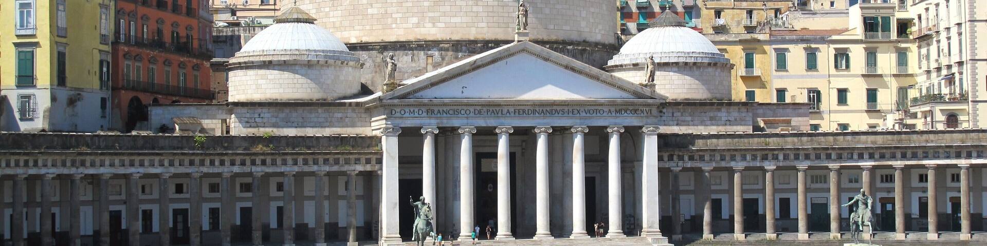A large domed building with columns and statues, surrounded by historic buildings.