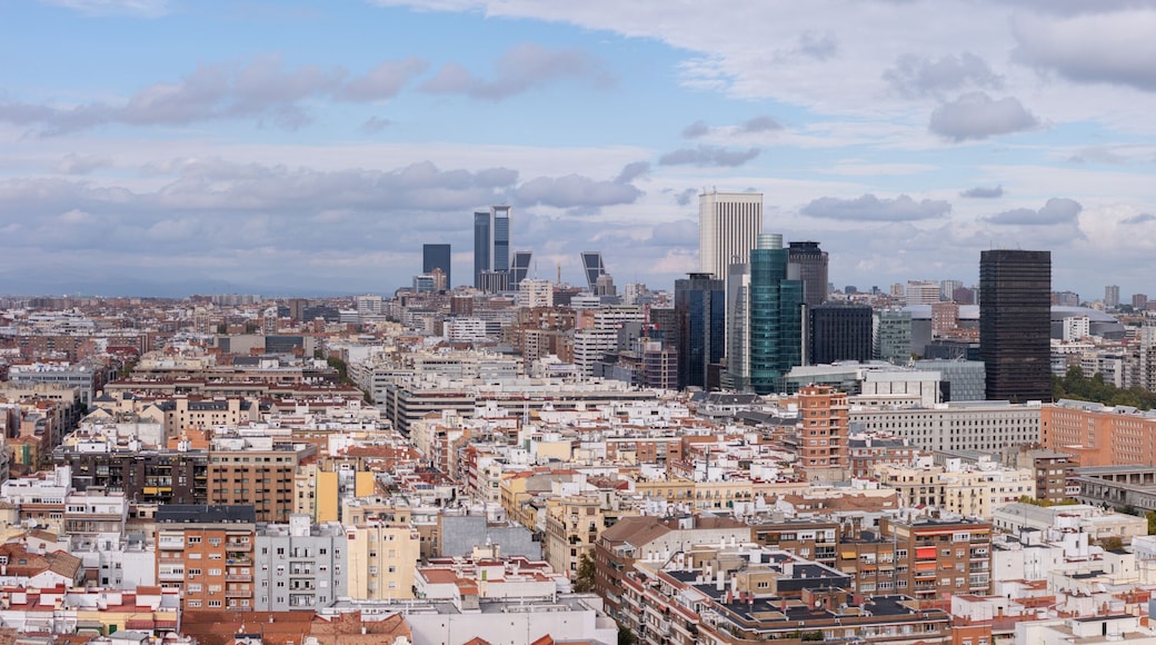 Aerial view of a city's rooftops and modern skyscrapers piercing the skyline under a cloudy sky, Madrid, Spain.