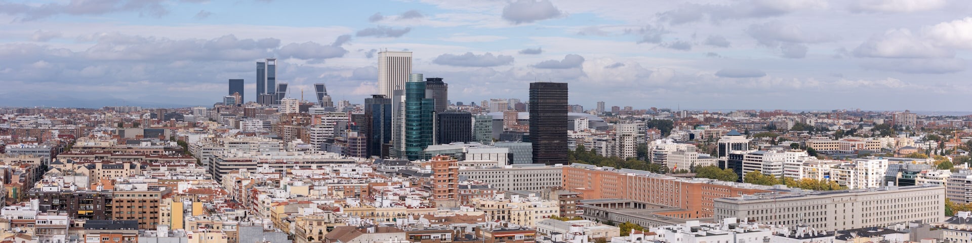 Aerial view of a city's rooftops and modern skyscrapers piercing the skyline under a cloudy sky, Madrid, Spain.