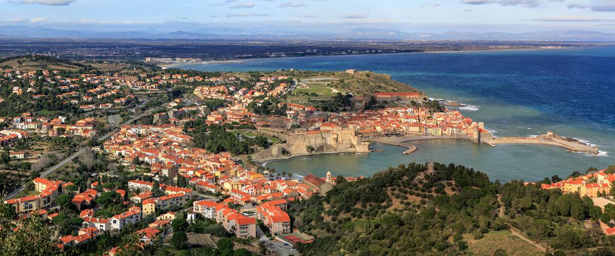 A coastal town with a historic fort, red-roofed buildings, and a bay.