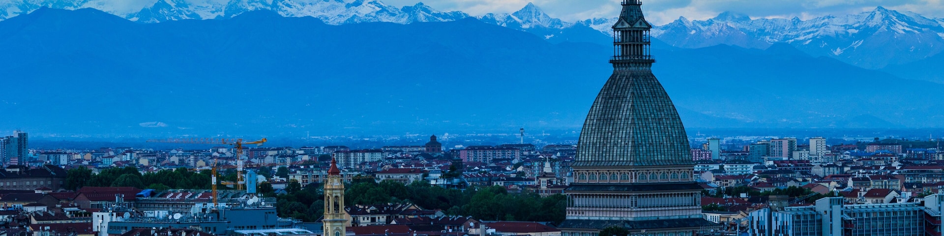 Mole Antonelliana dominating the city of Turin with the still snow-capped Alps in the background in spring, seen at sunset from the Monte dei Cappuccini