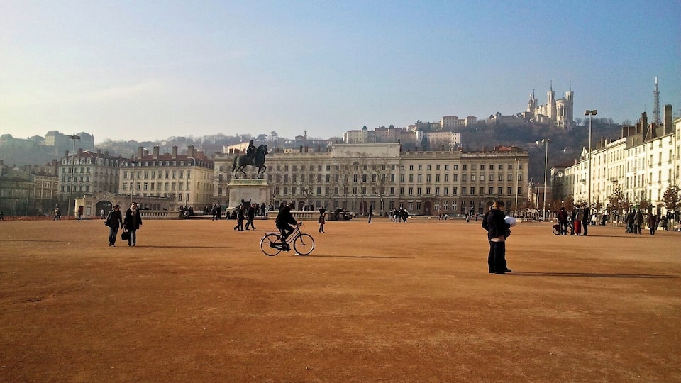 A wide open plaza with a statue of a man on horseback, surrounded by historic buildings and a clear sky.