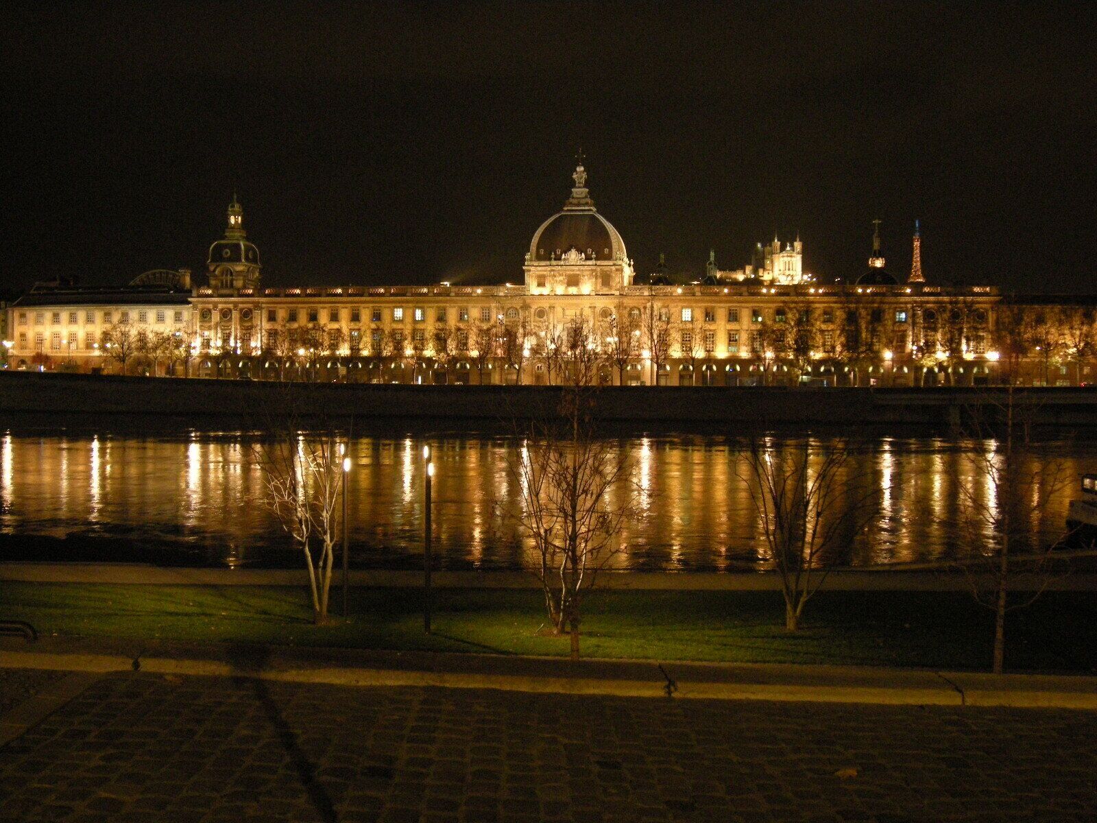 Un río con un gran edificio iluminado al fondo.