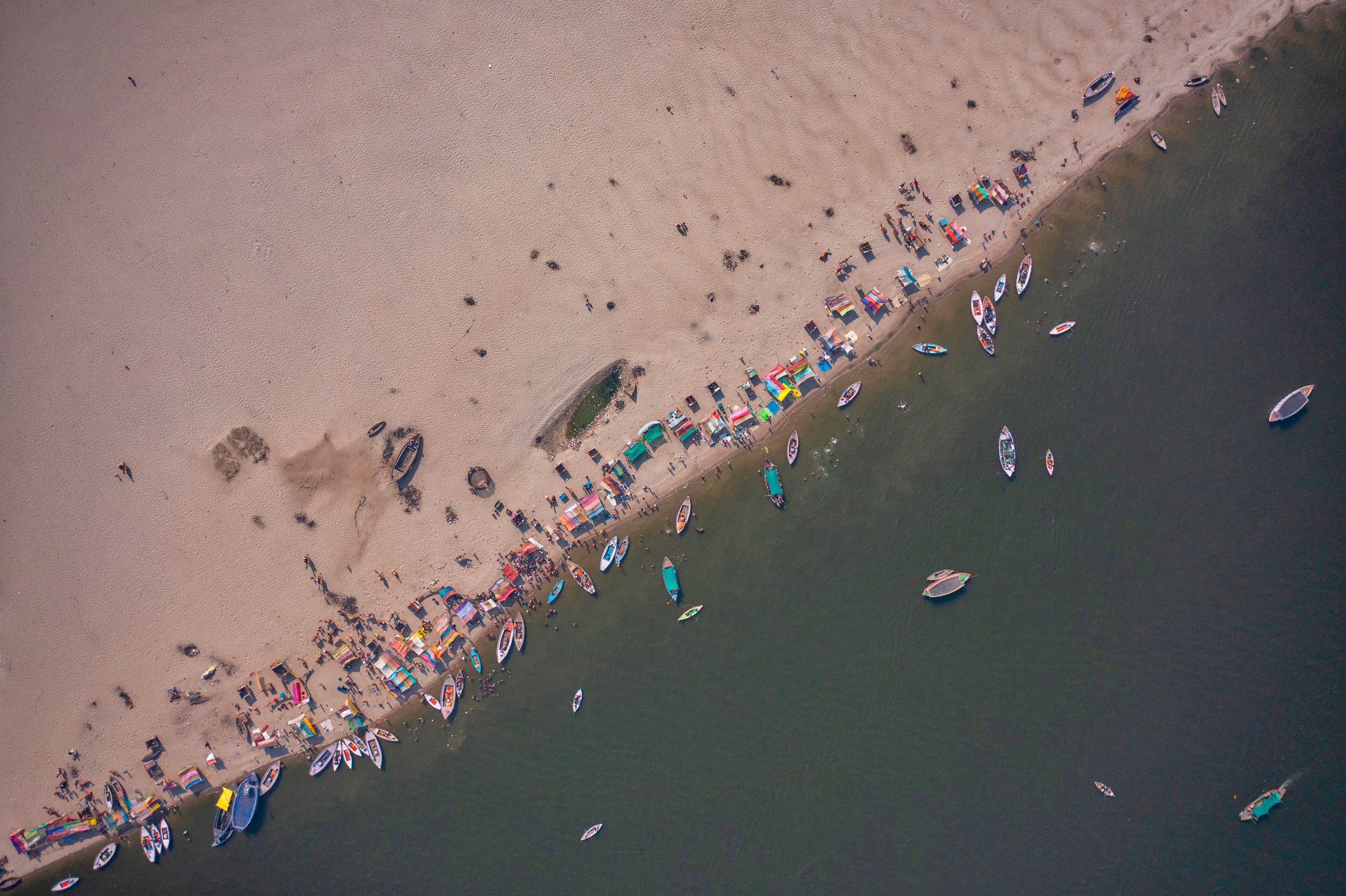 An aerial view of a beach with numerous boats and people.