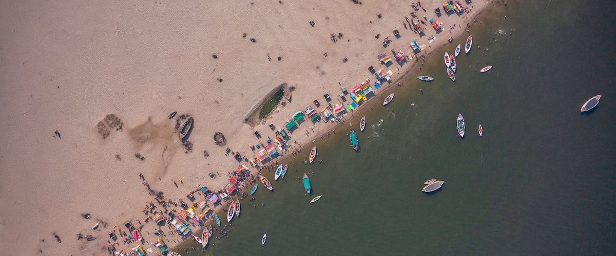 An aerial view of a beach with numerous boats and people.