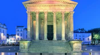 A classical neoclassical building with columns and a pediment, illuminated at dusk.