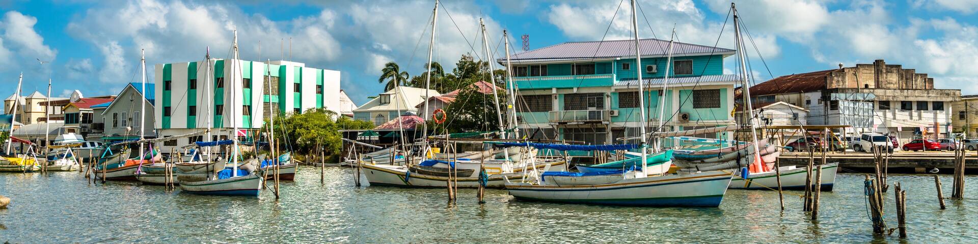 A harbor with boats docked, buildings, and a partly cloudy sky.