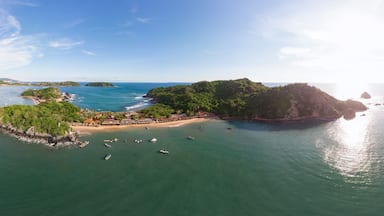 Vista aérea de una isla costera con playa, barcos y agua circundante.