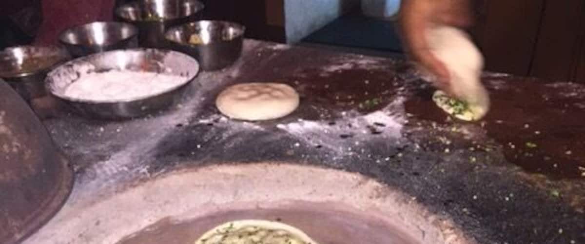 A traditional clay oven with dough inside, surrounded by various bowls and ingredients.