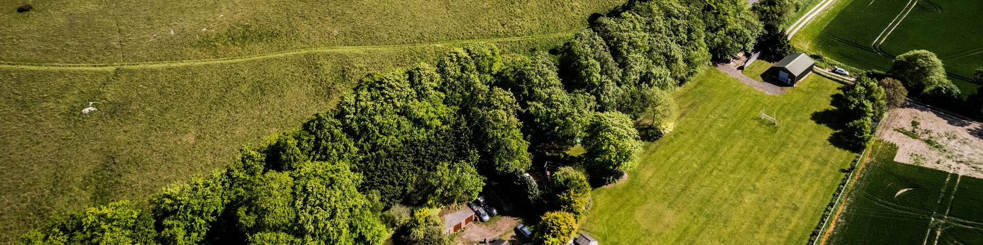 An aerial view of a countryside with a large white silhouette of a lion on a grassy hill.
