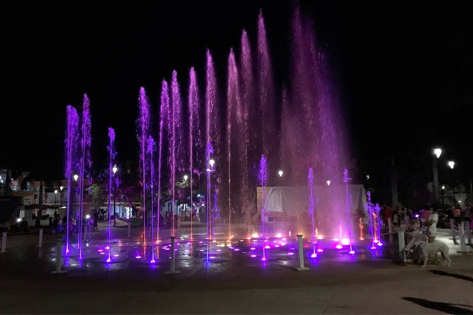 Una fuente iluminada con luces moradas durante la noche.