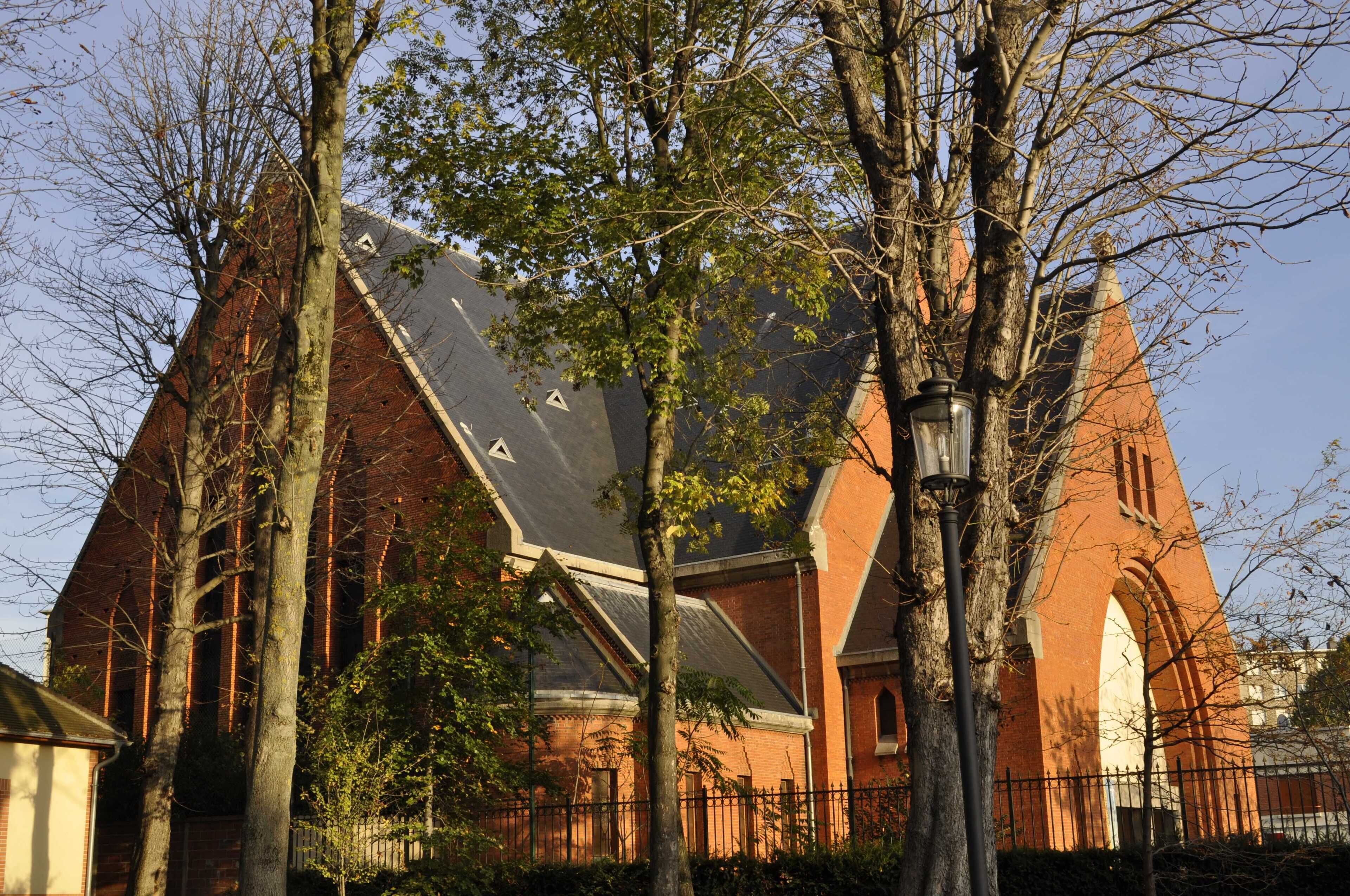 A large brick church with a steep roof and a tall bell tower.