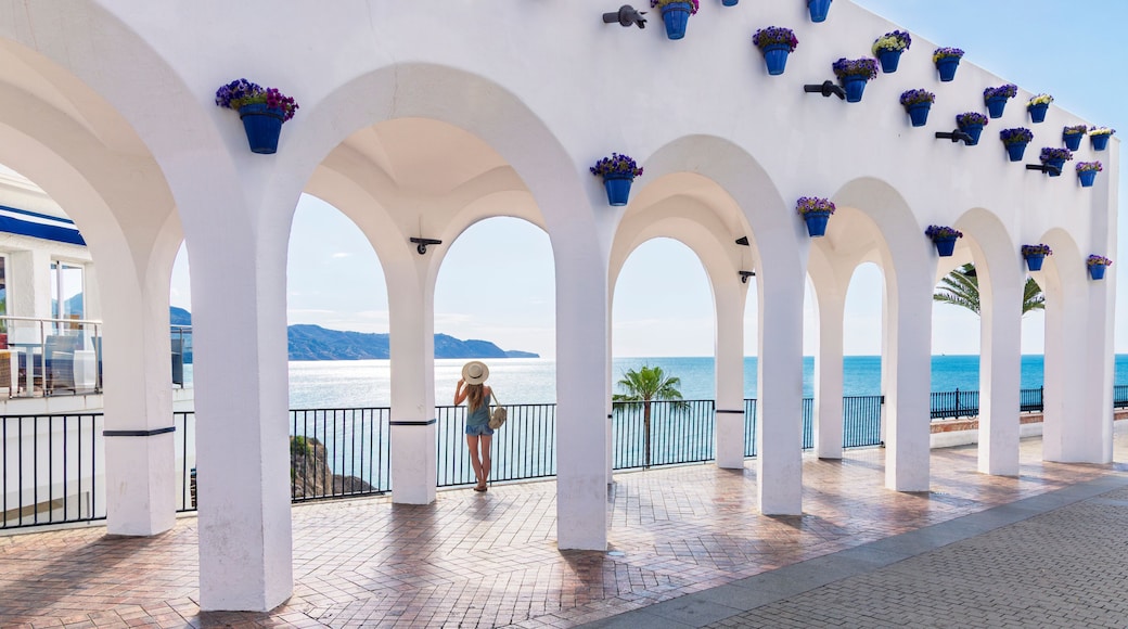 balcon de europa in nerja, andalusia, spain, white arches with blue flower pots overlooking the mediterranean sea and a woman traveler