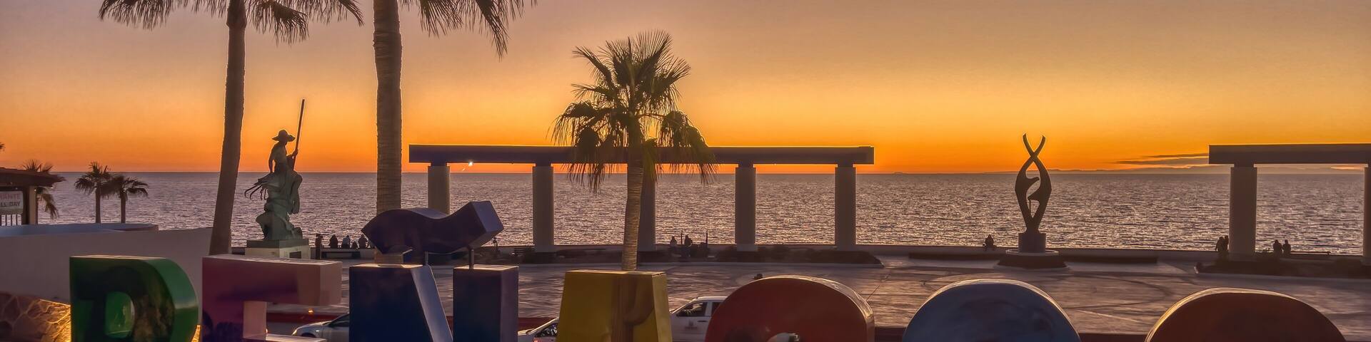 A sunset view with palm trees and the word 'PENASCO' spelled out in large letters.
