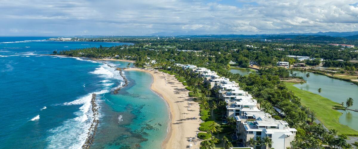 A coastal resort with beachfront villas, a sandy beach, and a golf course.
