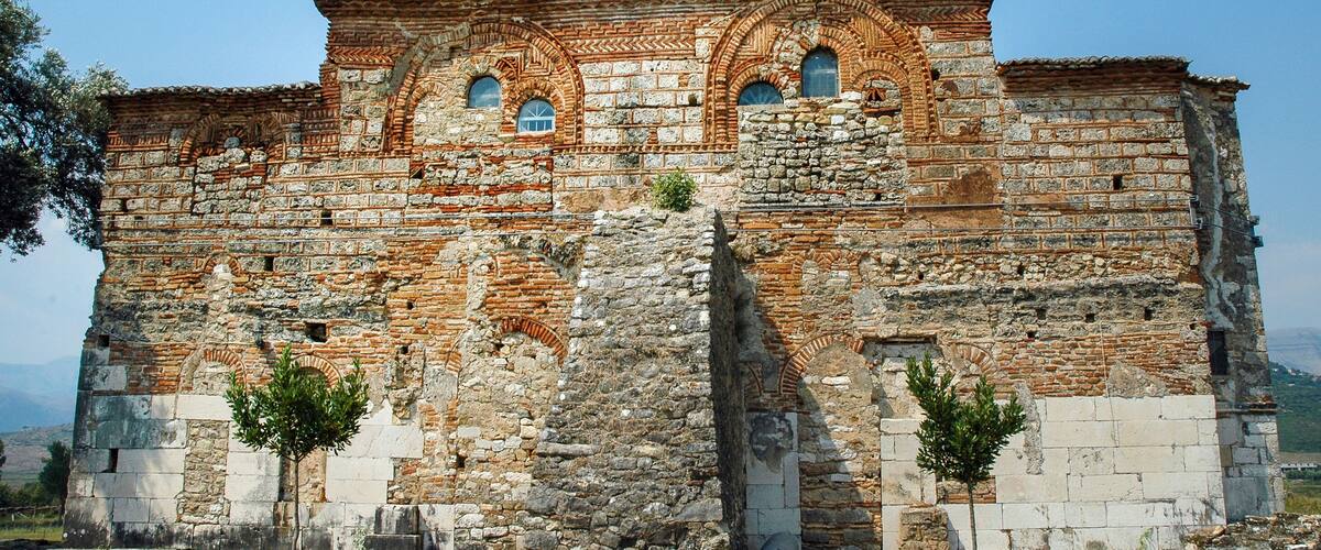 An ancient stone building with arched windows and a brick dome.