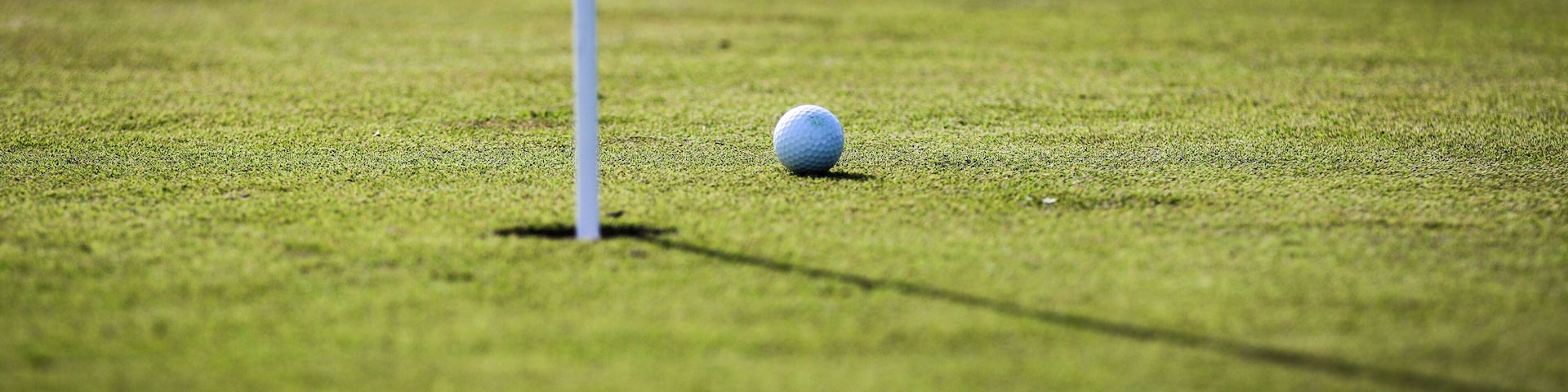 White golf ball next to putting green hole waiting to be tapped in at a golf course in Central Florida