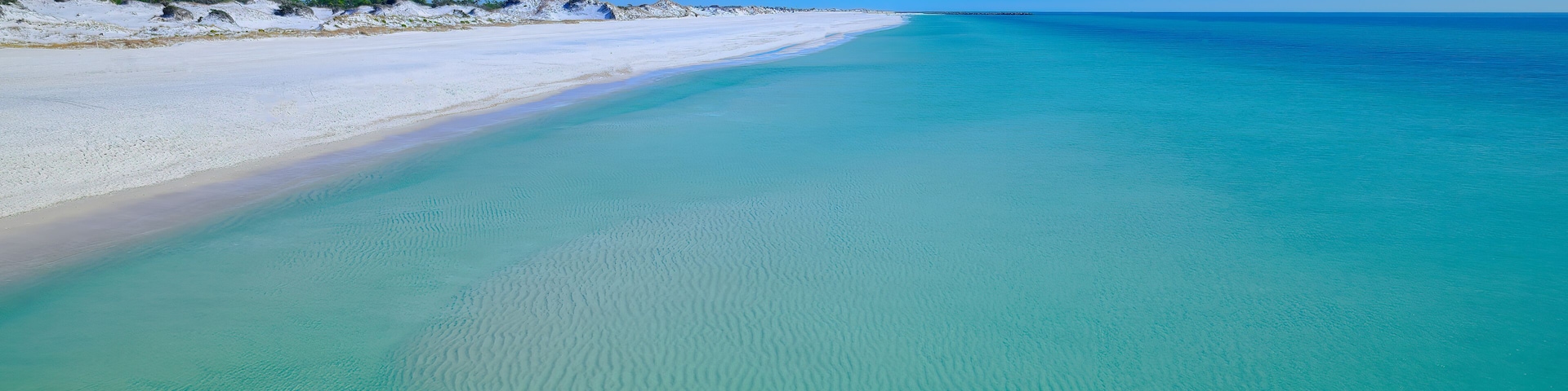 Calm emerald gulf of mexico water sugar white sand dunes at St. Andrews State Park Florida USA