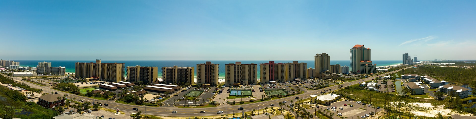 Paisagem costeira com edifícios altos, praia e marina.