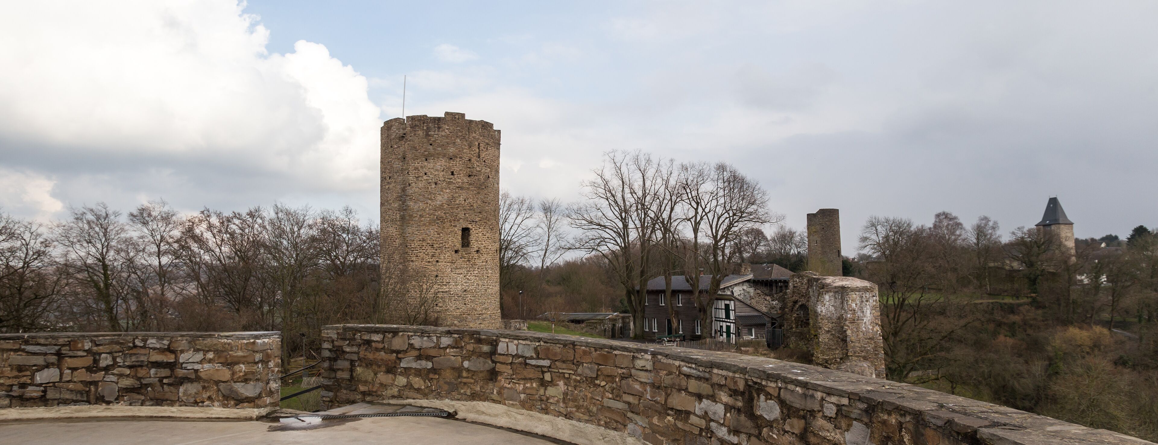 A stone bridge, a tall brick tower, and a traditional house in a rural setting.