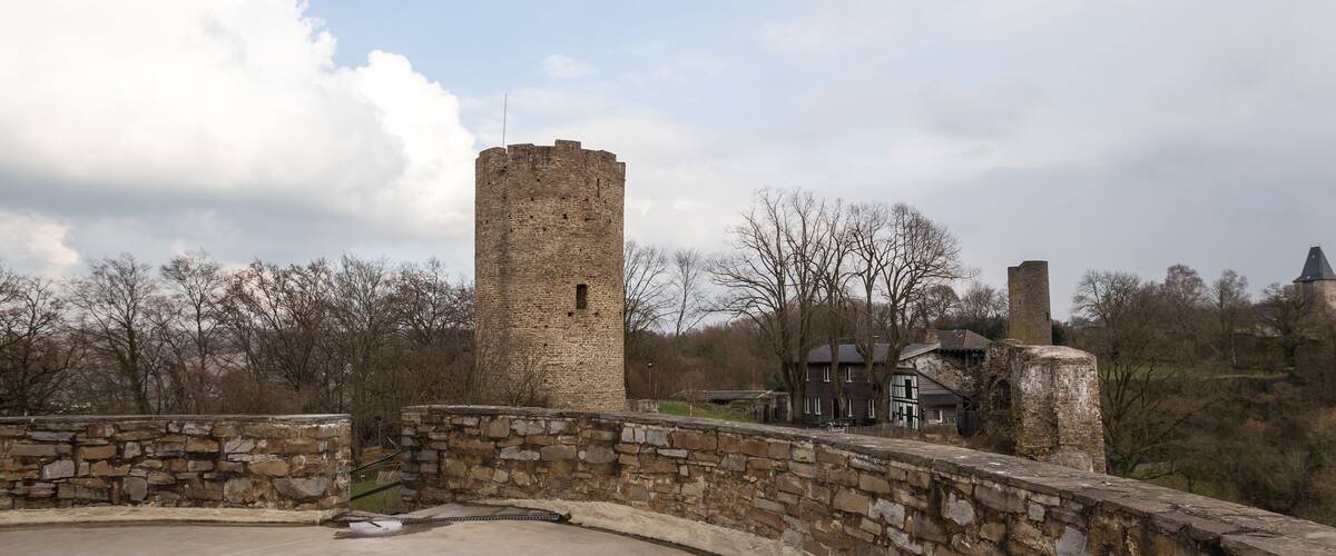 A stone bridge, a tall brick tower, and a traditional house in a rural setting.