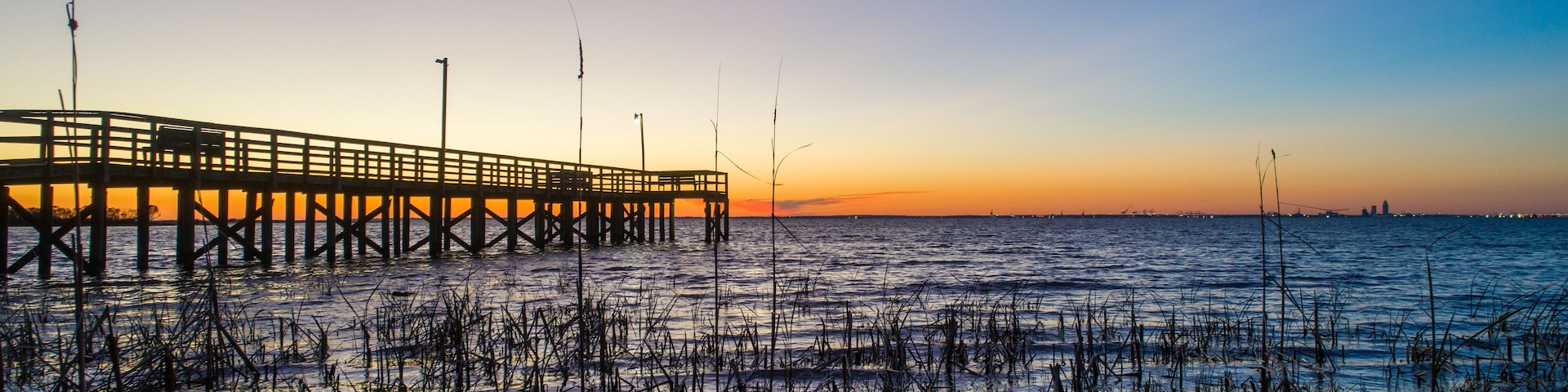 Un muelle que se adentra en aguas tranquilas al atardecer.