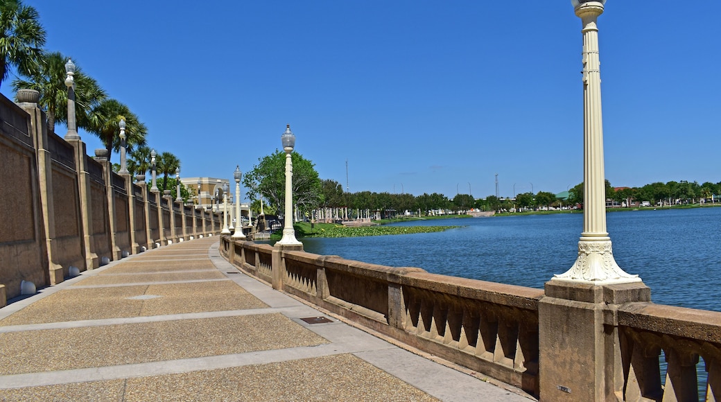 A bridge with ornate lamp posts, palm trees, and a calm river.