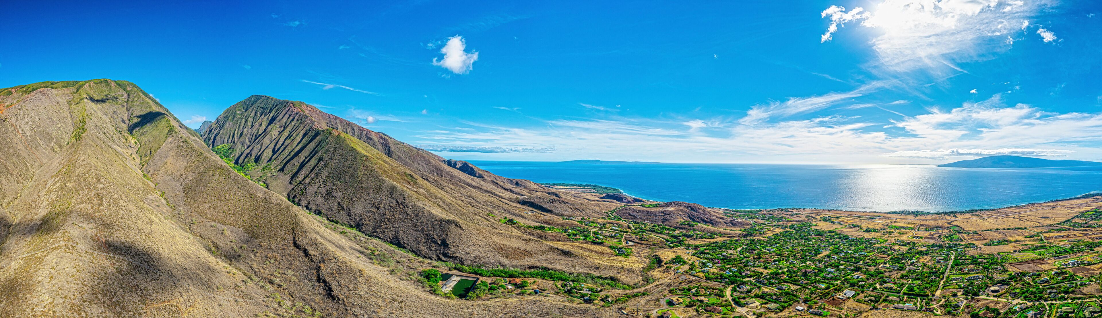 A mountainous landscape with a coastal town and a large body of water.