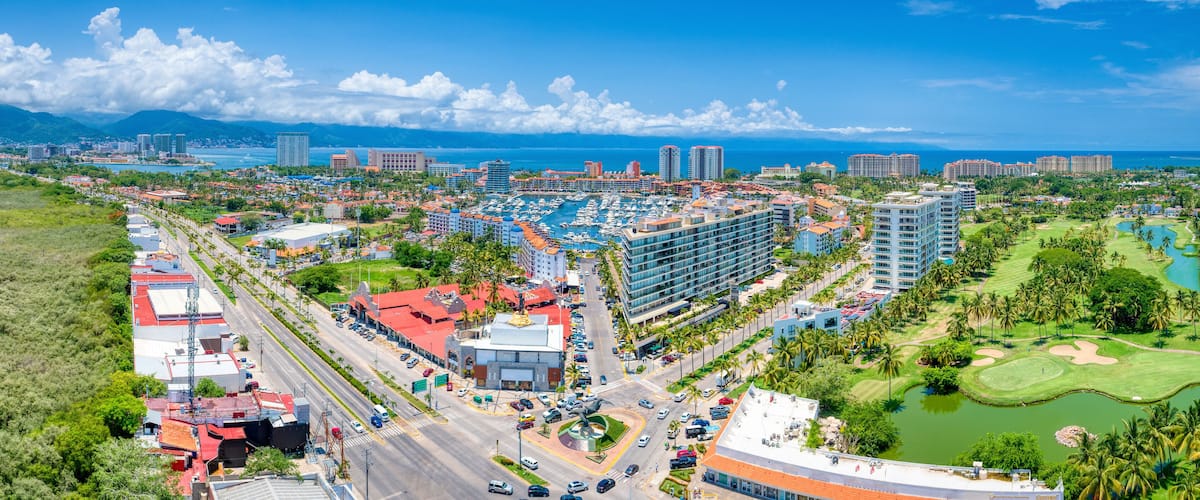 Un paisaje urbano costero con un puerto deportivo, edificios de gran altura y un campo de golf.