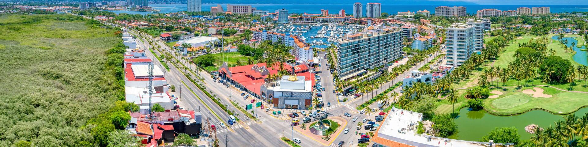 A coastal cityscape with a marina, high-rise buildings, and a golf course.