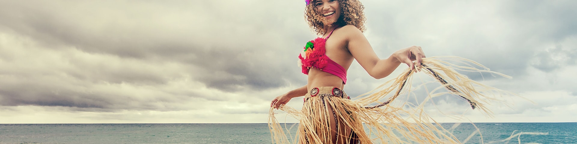 Happy and cheerful hawaiian woman portrait dancing on the beach, letterbox