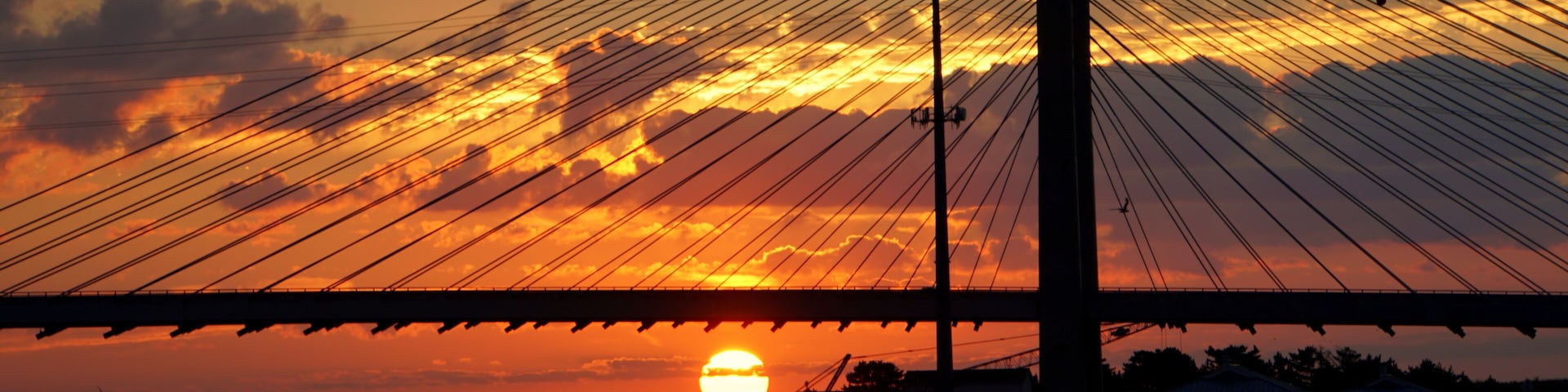 Eine Brücke im Abendrot, die Sonne spiegelt sich im Wasser.
