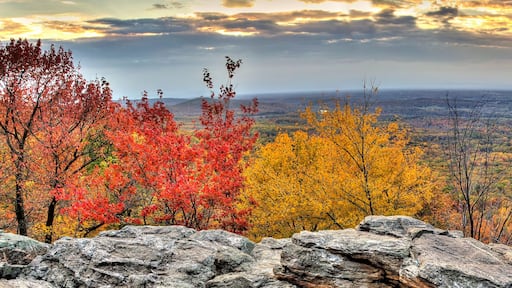 A mountainous landscape with autumn foliage, rocky outcrops, and a valley below.