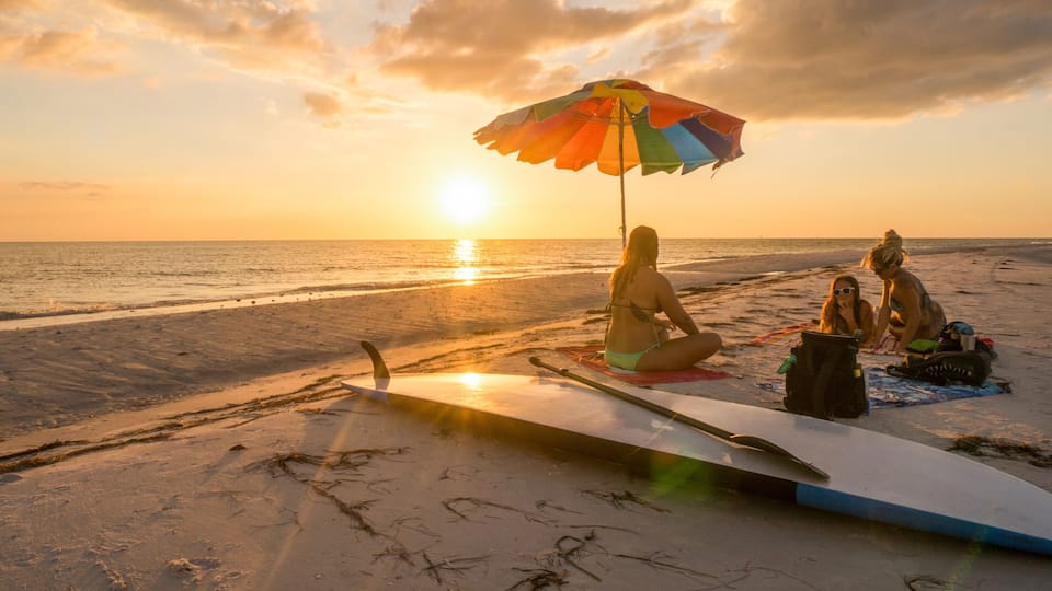 LOVERS KEY, FORT MYERS BEACH, FLOIRDA/USA 11/4/15: Girlfriends enjoying the sunset on the beach underneath a rainbow unbrella.