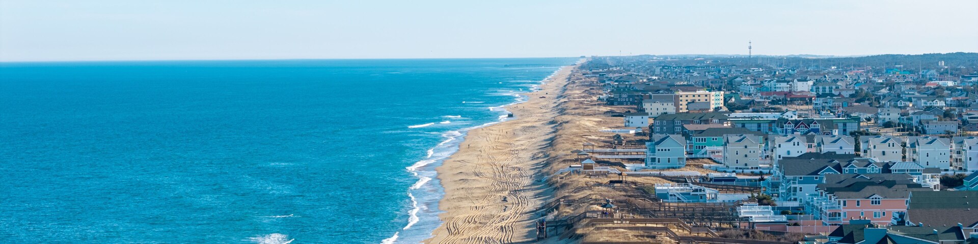 Kill Devil Hills, North Carolina, aerial view of the Atlantic coastline featuring sandy beaches, vacation homes, and the expansive Outer Banks landscape.