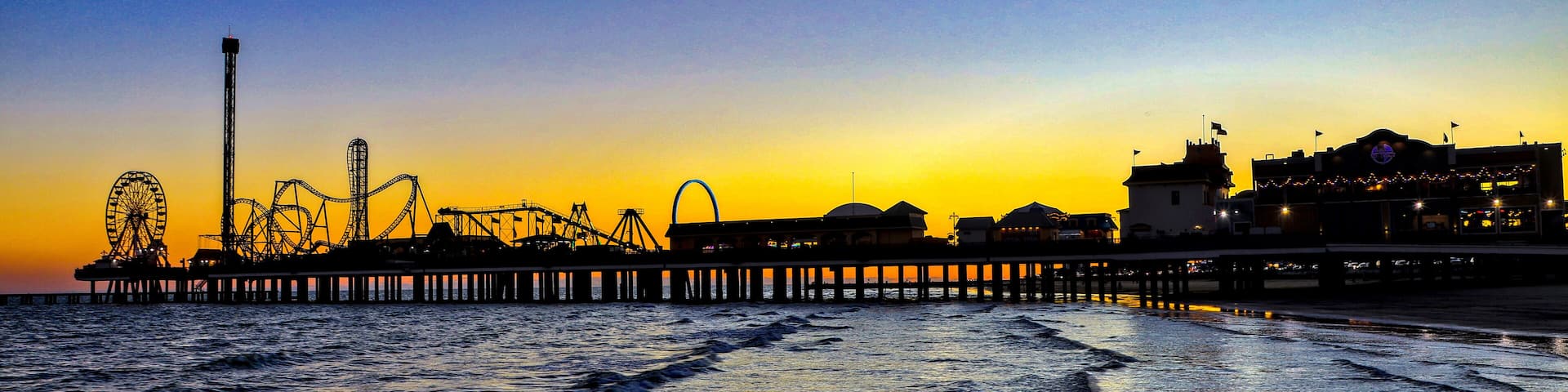 Galveston, Texas - 11-23-2024. A panorama of an amusement park on a large pier stretching out into the Gulf of Mexico at sunset.
