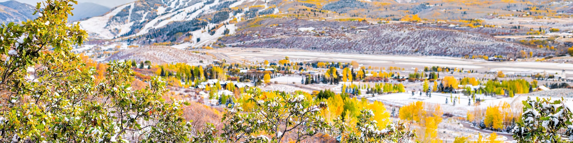 Aspen Colorado mountains roaring fork valley high angle view of small airport during autumn fall season with snow covered tree foliage