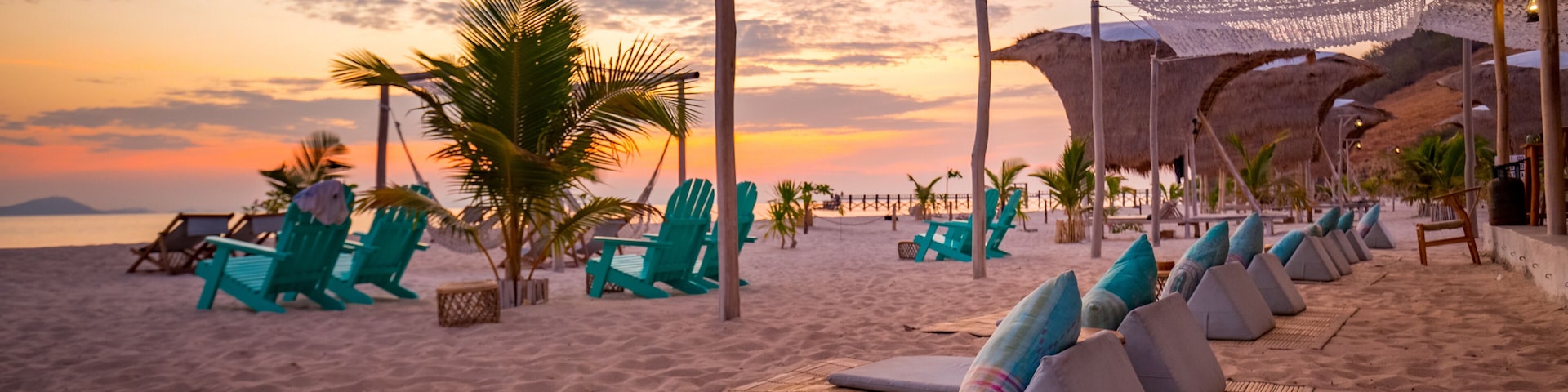 Beach club with chairs and umbrellas on beach during sunset