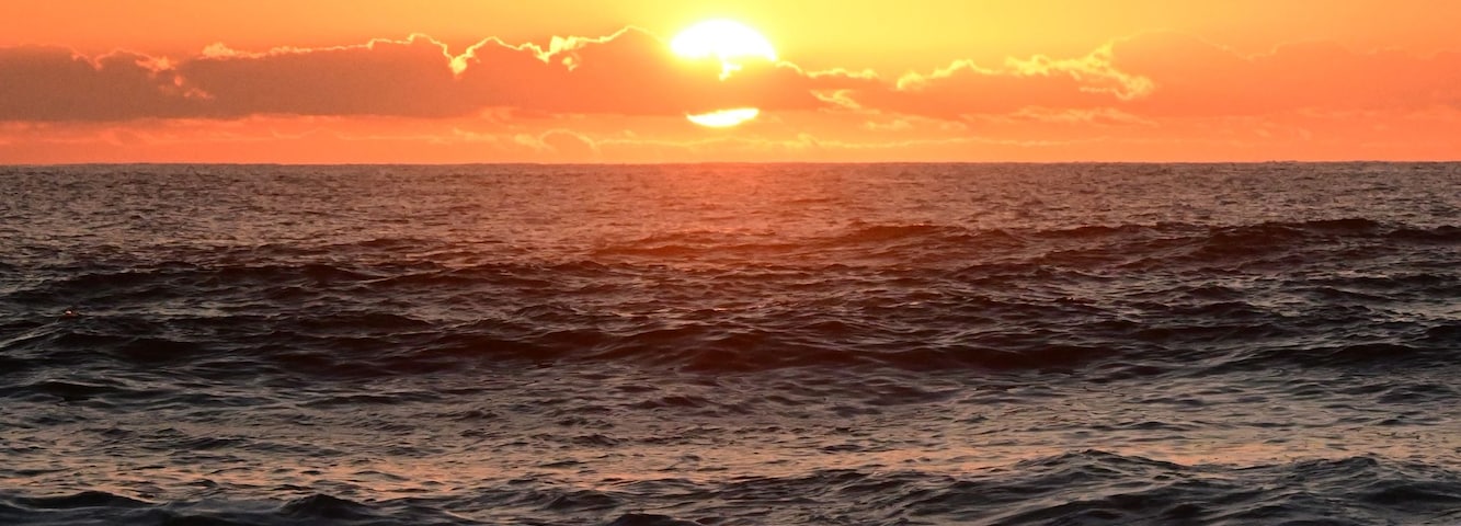 A sunset over the ocean with waves.