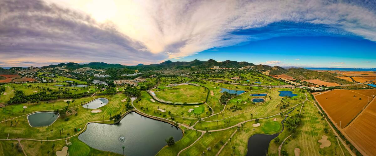 A golf course with multiple ponds and a mountainous backdrop.