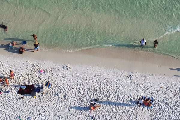 Panorama diverse crowed people swimming, relaxing on sugar white sandy shoreline, turquoise water, South Walton beach, Destin, Florida, USA, colorful tents, canopy, lounge chairs