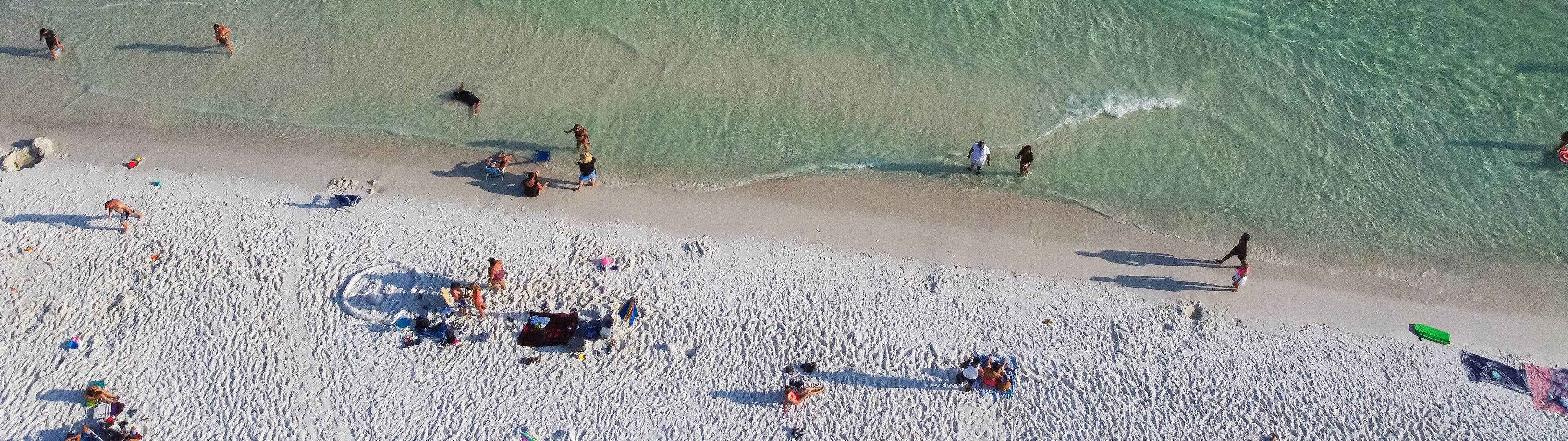 A crowded beach with people sunbathing and swimming.